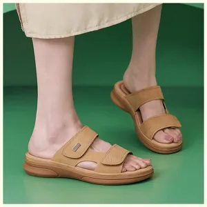 Close-up of tan wedge sandals featuring adjustable velcro straps and a metal logo detail