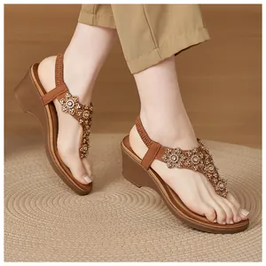 Detail of wedge sandals with rhinestone flowers and elastic back strap on a wooden floor