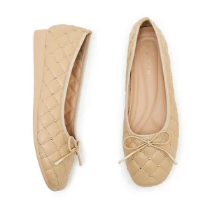 Details gesteppter Ballerinas mit goldenen Nieten und einer zarten Schleifenverzierung