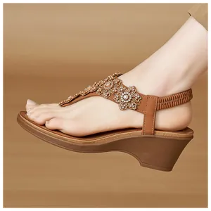Detail of wedge sandals with rhinestone flowers and synthetic leather footbed on feet