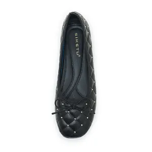 Makroansicht schwarzer Ballerinas mit Steppmuster, Goldnieten und Schleife
