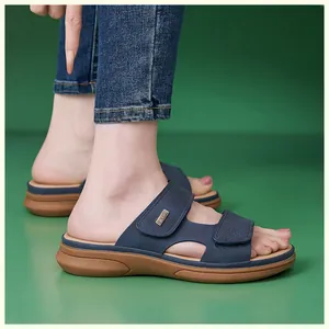 Detail shot of navy blue wedge sandals featuring a metallic EKCN logo plate and brown sole