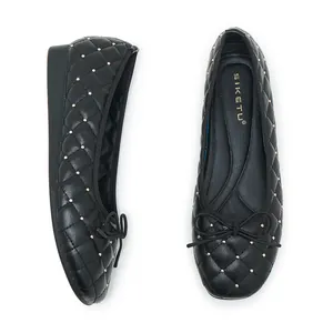 Nahaufnahme schwarzer gesteppter Ballerinas mit Goldnieten und Schleifendetails