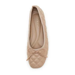Draufsicht auf beige gesteppte Ballerinas mit Goldnieten und zarter Schleife
