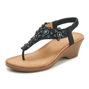 Detail of black wedge flip-flops with lace flower accents and sparkling rhinestones