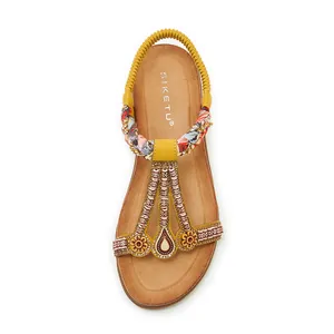 Détail de sandales bohèmes avec fleurs en perles et lanières aux motifs ethniques