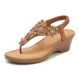 Macro shot of rhinestone floral embellishment on brown wedge flip-flop sandals