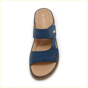 Detail of dark blue wedge sandals with perforated leather straps and gold metal logo