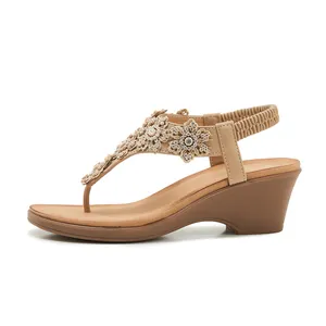 Close-up of beige wedge sandals with rhinestone floral lace and pearl embellishments