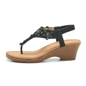 Detail of black wedge sandals featuring rhinestone flower lace and elastic back strap