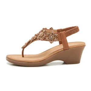 Close-up of brown platform wedge sandals featuring 3D floral embroidery and rhinestones