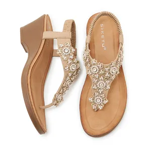 Detailed view of apricot wedge sandals featuring rhinestone flower petals and elastic straps