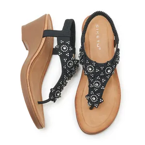 Detail of wedge sandals showing intricate black rhinestone flowers and elastic back strap