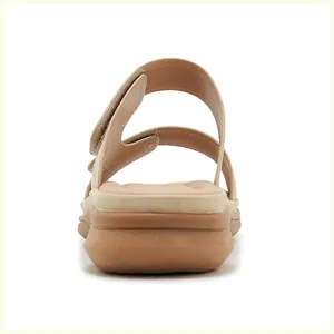 Detail of the adjustable velcro straps and cushioned wedge heel on beige sandals