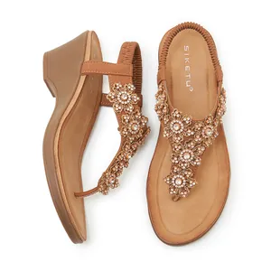 Macro detail of brown wedge sandals with decorative rhinestone flower and beaded T-strap design