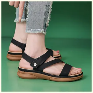 Detail of black faux leather straps and brown wedge sole with round metal buckle