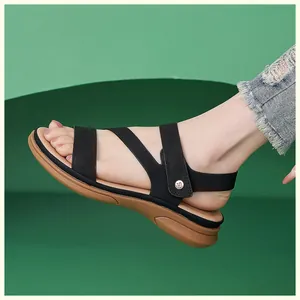 Detail of black cross-strap sandals with brown platform sole and gold buckle accent