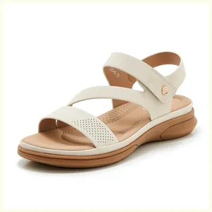 Detail view of beige wedge sandal featuring laser-cut patterns and adjustable velcro straps