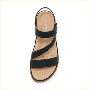 Top view detail of black cross-strap sandals with beige dotted comfort footbed
