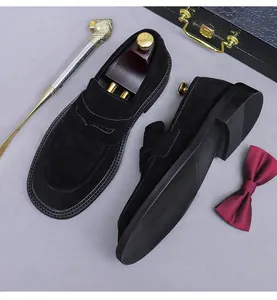 Detail of black suede penny loafers with a lion-head shoehorn and elegant accessories