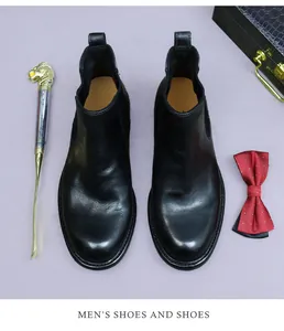 Vue à plat de bottines Chelsea en cuir noir avec chausse-pied et accessoires chics