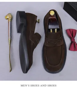 Detail view of premium dark brown suede loafers with wooden shoe tree and luxury props