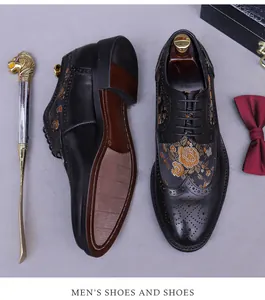 Detail of men's black brogue dress shoes with floral embroidery and classic wingtip carving