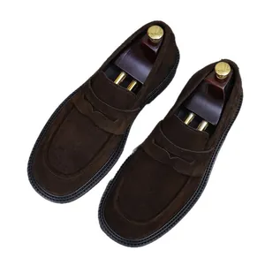 Mens dark brown suede penny loafers with wooden shoe trees on a white background