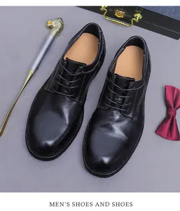 Bovenaanzicht van zwarte leren Derby schoenen met stiksels tegen een grijze achtergrond