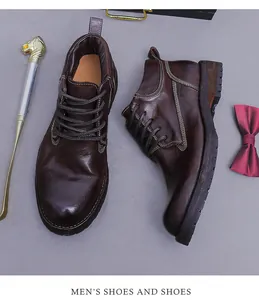 Detail of dark brown leather boots with wax finish and double stitching on gray surface
