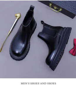 Close-up of black leather Chelsea boots with golden lion shoehorn and premium packaging