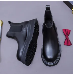 Detailed view of black polished leather Chelsea boots with thick lug sole and elastic side