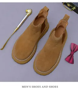 Detailed view of brown suede Chelsea boots featuring elastic side and white stitching