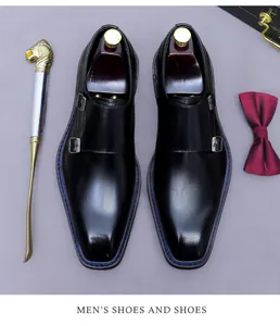 Vista dall'alto di scarpe monk in pelle nera con fibbie d'argento e cuciture blu