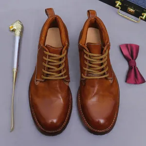 Vintage brown leather work boots with yellow laces and premium stitching on grey surface