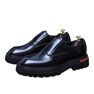 Glänzende schwarze Herren-Loafer mit dicker Gummisohle und orangem Fersendetail auf Weiß