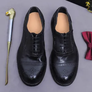 Klassische schwarze Leder Oxford Brogue Schuhe mit Flügelkappe für Herren auf grauem Grund
