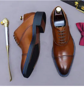 Detail of brown leather oxford shoes with blue stitching and classic cap toe design