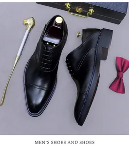 Detail of black leather oxford shoes with blue stitching and business accessories