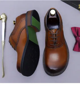 Detailed view of brown leather Oxford shoes with wide round toe and brogue pattern