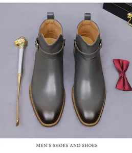 Detail shot of men's leather boots with buckle strap, metal zipper and lion head shoehorn