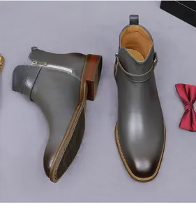 Detail of grey leather men boots with side zipper, buckle strap, and non-slip sole