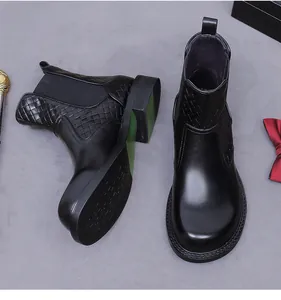 Dettaglio degli stivaletti Chelsea in pelle nera con trama intrecciata e suola verde neon