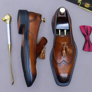 Mocassins Brogue en cuir marron avec glands et surpiqûres bleues sur fond gris