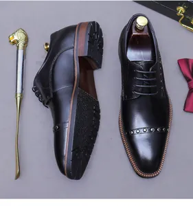 Close-up of black leather business shoes featuring stylish metal rivet details and laces