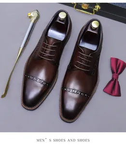 Top view of dark brown leather oxford shoes with metal rivets and business accessories