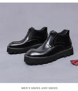 Detail of black glossy leather boots with Brogue carving and front zipper on chunky soles