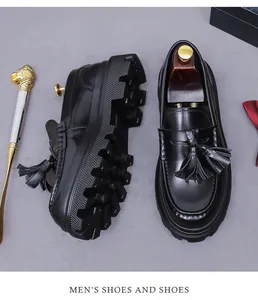 Top view of black tassel loafers with chunky soles, wooden shoe trees and gold horn