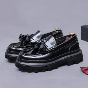 Men's black patent leather tassel loafers with chunky platform rubber sole shown in profile