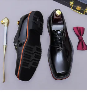 Dettaglio delle scarpe Derby in vernice nera con suola arancione e accessori da uomo eleganti